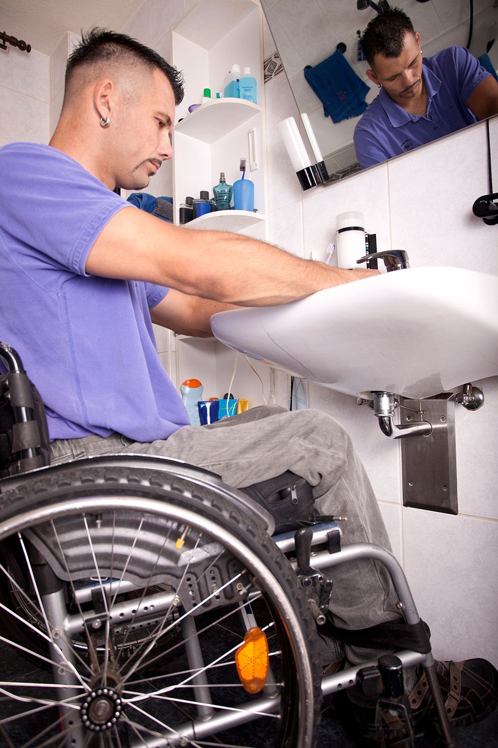 Behinderter junger Mann im Rollstuhl beim Händewaschen